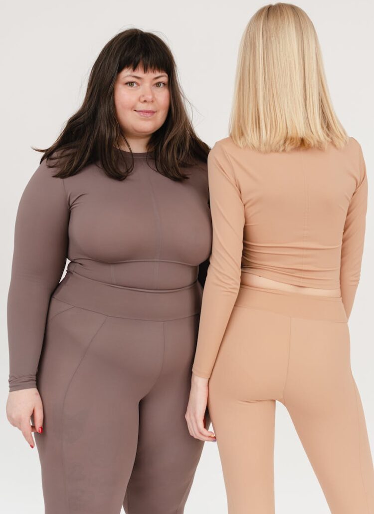 young obese and slender women standing in white studio